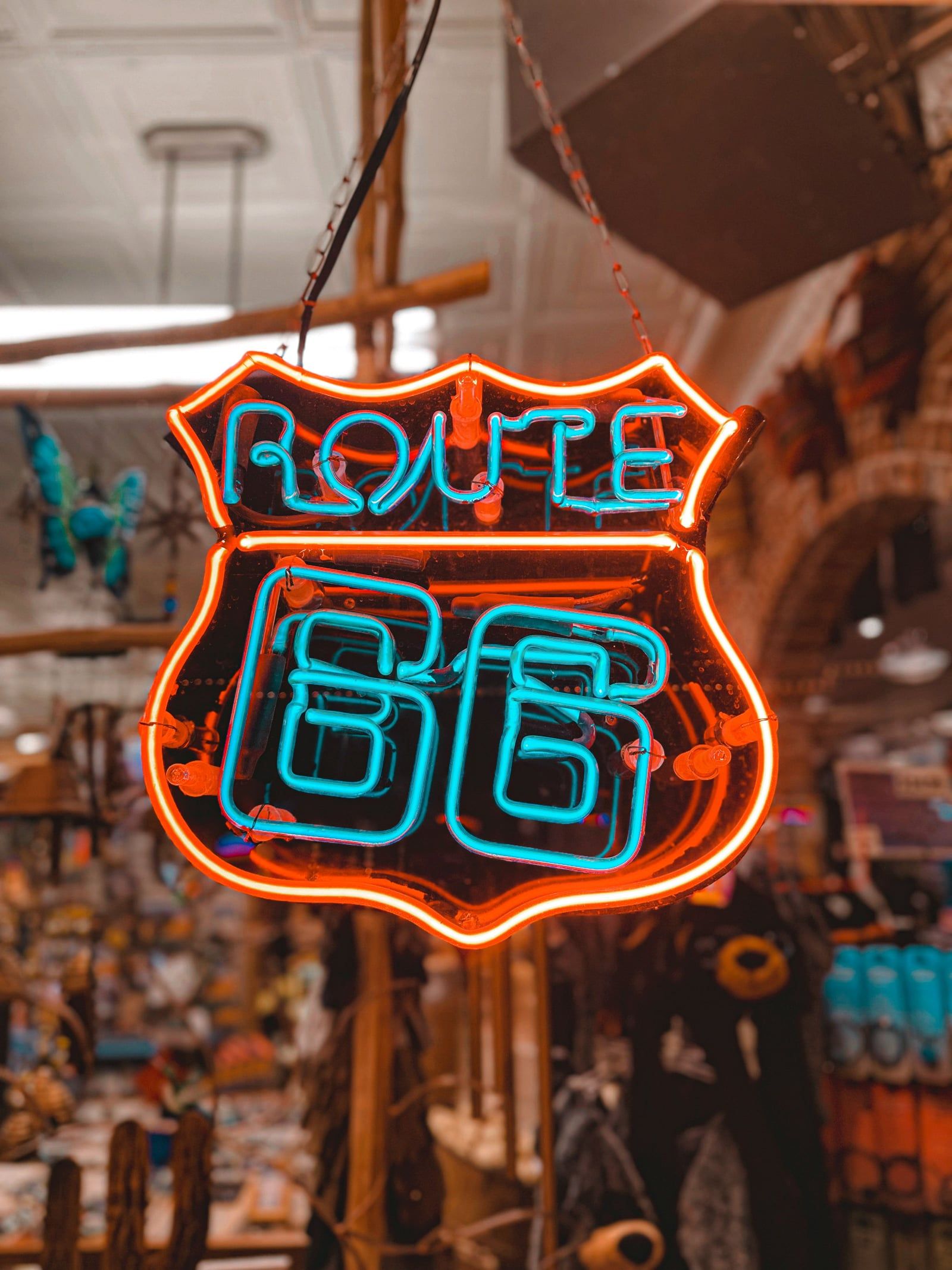 Neon Route 66 shield sign glowing red and turquoise in a roadside shop